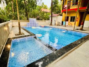a swimming pool with blue water in front of a building at Deepdaya Cottage in Alibag