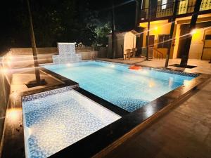 a swimming pool at night in a building at Deepdaya Cottage in Alibag