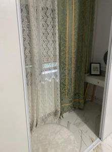 een douche met een douchegordijn en een spiegel bij Lemora Apartments in Focşani