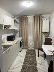 een keuken met witte kasten en een tafel. bij Lemora Apartments in Focşani
