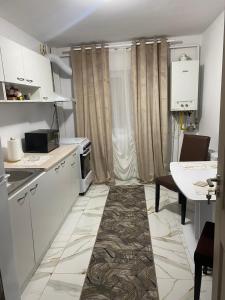 een keuken met witte kasten en een tafel en een tafel bij Lemora Apartments in Focşani +2 foto's