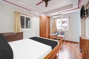 PatnaHotel O Arvind Inn的一间卧室，里面有一张床、一张桌子和一把椅子 更多25张照片