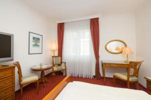 Casa Stefano في فيينا: غرفة فندقية تحتوي على سرير ومكتب وتلفزيون