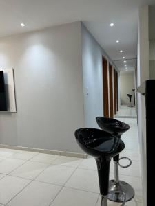 ein schwarzer Hocker in einem Raum mit einer Wand in der Unterkunft Cabo de Santo Agostinho Apartmento in Cabo de Santo Agostinho