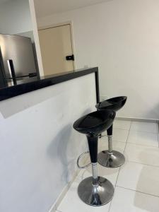 ein schwarzer Hocker in einem weißen Raum mit einem Spiegel in der Unterkunft Cabo de Santo Agostinho Apartmento in Cabo de Santo Agostinho
