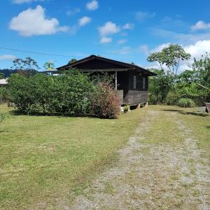 a house in a field with a dirt road at Célia in Matoury