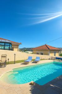 Studio de la Villa Thérèse, Piscine & Jardin في سان لوران دو فار: حمام سباحة مع كرسيين ومنزل