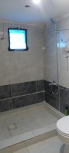 a bathroom with a shower and a toilet and a window at Alnwatif Gate guest house Dana nature reserve in Dana