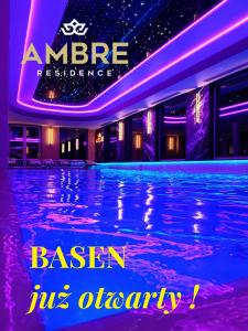 韦巴Rezydencja AMBRE的紫色灯的建筑中的游泳池