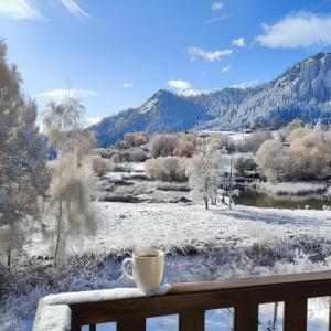 a cup of coffee sitting on a balcony with a snow covered field at Апартамент "Rodopi" с Гледка към Езеро Безплатен Подземен Гараж in Smolyan