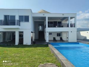 a white house with a swimming pool in front of it at Casa Playa Eugen beach house with pool in El Morro