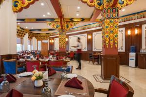 a restaurant with tables and chairs and a person in the background at Hotel Gyalpo Residency - A Mountain View Luxury Hotel in Leh in Leh