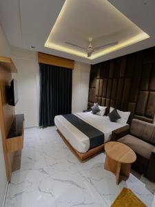 ein Schlafzimmer mit einem großen Bett und einer Couch in der Unterkunft Hotel Pacific Inn in Ahmedabad