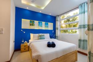 a blue bedroom with a bed with two pairs of shoes on it at White Dolphin in Hulhumale