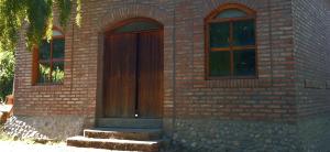 un edificio de ladrillo con puerta de madera y 2 ventanas en Finca Fraschetti, en El Bolsón