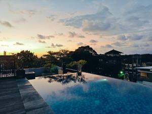 a large swimming pool with a sunset in the background at Palette Legian Beach in Legian