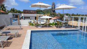 ein Swimmingpool mit Stühlen und Sonnenschirmen auf einem Gebäude in der Unterkunft Pousada Village Premiere in Fernando de Noronha