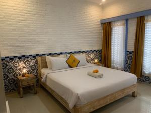 a bedroom with a bed with white sheets and yellow pillows at Sunflower Stay And Surf in Canggu