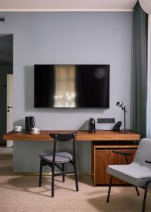 Un escritorio con dos sillas y un televisor en una pared. en Wroclaw Hotel, en Wroclaw