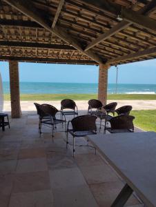 eine Terrasse mit Stühlen, einem Tisch und Strand in der Unterkunft Pousada Pé na Areia Morro Branco in Beberibe