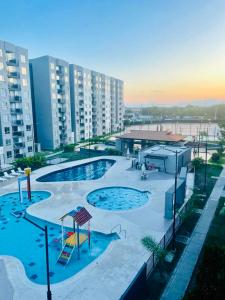 una piscina all'aperto con parco giochi ed edifici di Apartamento con Piscina en Ricaurte a Ricaurte