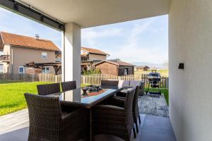 a patio with a table and chairs and a large window at Hiša Urma in Celje