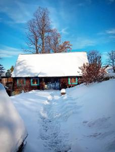 a snow covered cabin with a snow covered roof at Stodoła Głębuczek in Mystków
