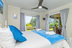 a bedroom with a large white bed with blue pillows at Sea-Renity 10 in Umdloti
