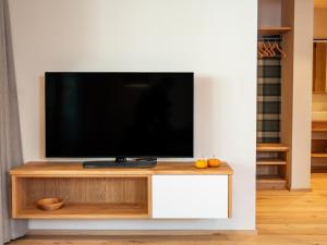 una TV a schermo piatto seduta sopra un centro di intrattenimento bianco di Kreithner luxury apartments a Vandoies