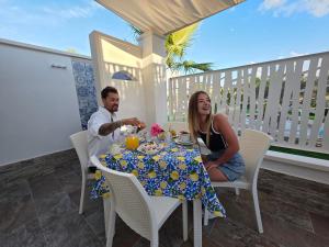 Ein Mann und eine Frau, die an einem Tisch auf einem Balkon sitzen in der Unterkunft Mimma house in Lampedusa