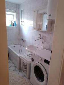 Un baño con lavadora y lavabo. en Apartman Čeliković, en Bosanski Šamac