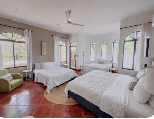 a bedroom with two beds and a couch and windows at Hacienda La Luna Luxury Private Villa in Potrero