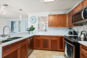 a kitchen with wooden cabinets and a clock on the wall at Island Paradise Resort Villa in Honokai Hale