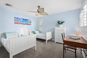 a bedroom with white furniture and a ceiling fan at Island Paradise Resort Villa in Honokai Hale