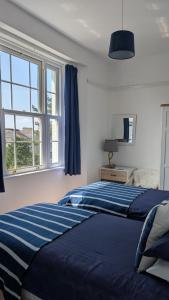 two beds in a bedroom with two windows at Rose Court Holiday Apartments in Torquay