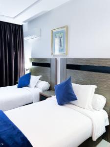 2 Betten in einem Hotelzimmer mit blauen Kissen in der Unterkunft Tanger Med Hotel, Conference & Catering in Ghdar Defla