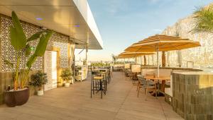 ein Restaurant mit Tischen, Stühlen und Sonnenschirmen in der Unterkunft Ribera de Triana Hotel in Sevilla