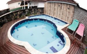 a large swimming pool on a wooden deck with two chairs at Castelinho Solemar - Suíte Premium com Banheira Privativa e Ar in Praia Grande