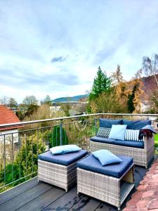 a balcony with two ottomans and two chairs on a deck at Traumhaftes Apartment mit Dachterrasse und Schlossblick in Marburg an der Lahn
