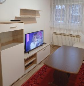 a living room with a table and a flat screen tv at Daily rental apartment Travnik in Travnik