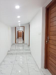 an empty hallway with white walls and a wooden door at KODIVEED Heritage in Alleppey
