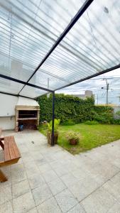 eine Terrasse mit einem Dach mit einem Tisch und einer Bank in der Unterkunft Casa Moras in Necochea + 14 Fotos