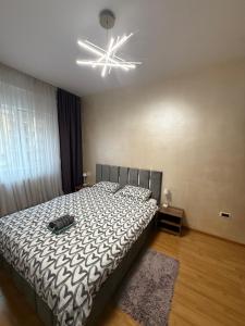 a bedroom with a bed with a black and white comforter at Comfort Stay Apartment - Free Parking & Wi-Fi in Chiajna