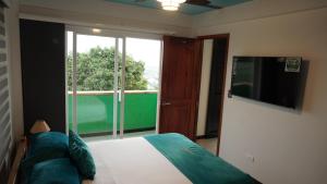 a bedroom with a bed and a tv and a window at Cristo Rey Hostal Campestre Cali in Cali