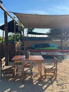 Ein Picknicktisch und zwei Stühle unter einem Zelt mit einem Surfbrett in der Unterkunft La Window Glamping in La Ventana