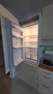 an empty refrigerator with its door open in a kitchen at Apartament Leśny Ząbki in Ząbki