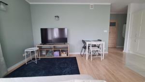 a living room with a tv and a table and chairs at Apartament Leśny Ząbki in Ząbki