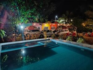 a swimming pool with cars parked in a yard at night at Madhurleela Villa in Alibaug