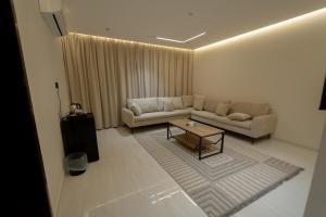 Una sala de estar con un sofá y una mesa de café. en عبر الاصالة, en Rafha