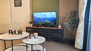 een woonkamer met 2 tafels en een flatscreen-tv bij Appartement Standing 5mn Village de Noël in Le Barcarès